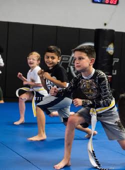 Smiling students wearing 10th Planet Beaumont gear learning jiu-jitsu.